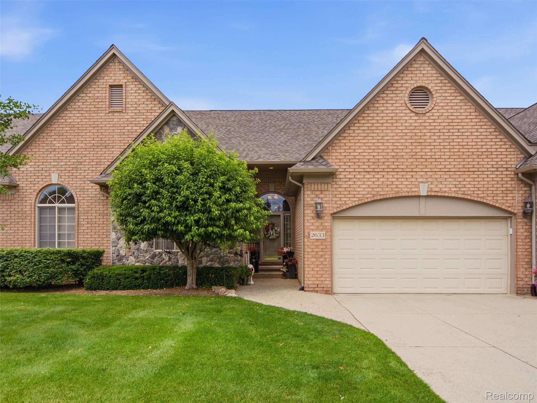 2633 Ridgecrest Drive Utica, MI 48316 - Photo 1 of 28 Brick and stone facade featuring a two-car garage, arched entry window, and mature landscaping