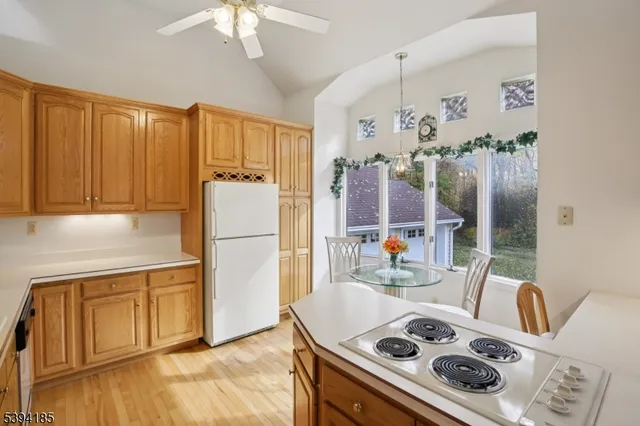 a kitchen with a refrigerator a stove a sink dishwasher and a dining table with wooden floor