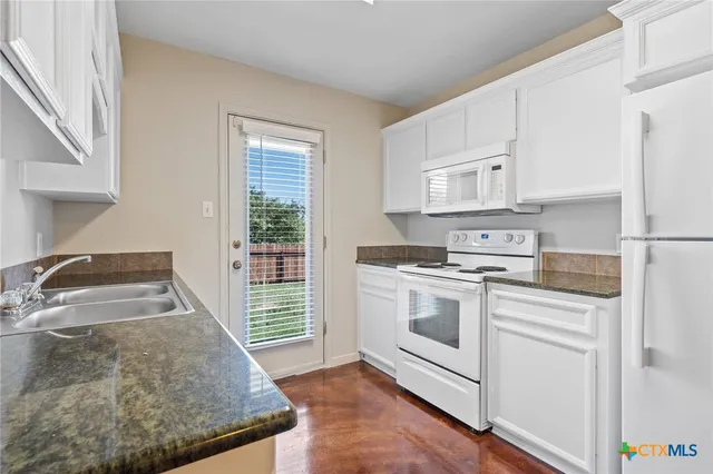 a kitchen with granite countertop white cabinets and white appliances