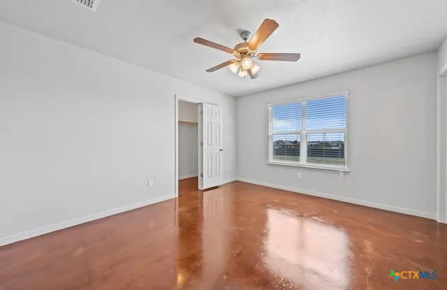 a view of an empty room with chandelier fan and wooden floor