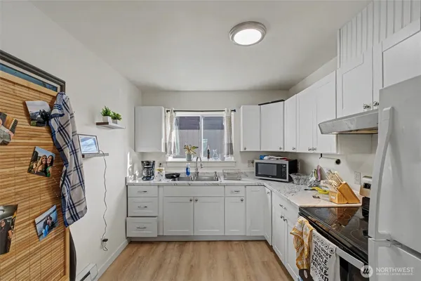 a kitchen with a sink dishwasher stove and white cabinets with wooden floor