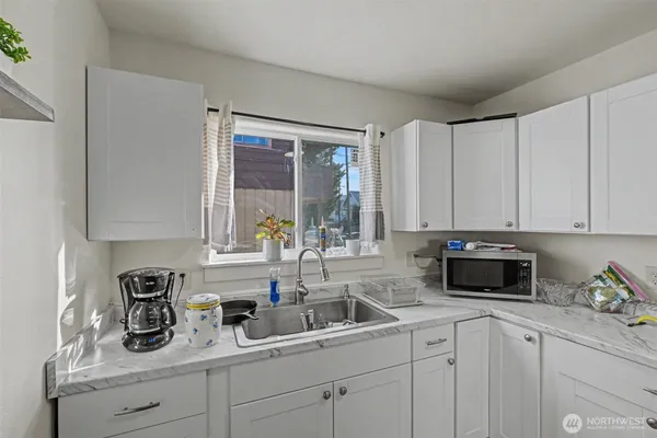 a kitchen with white cabinets and window