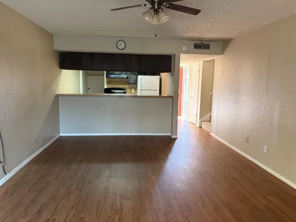 a view of a hallway with wooden floor and a ceiling fan