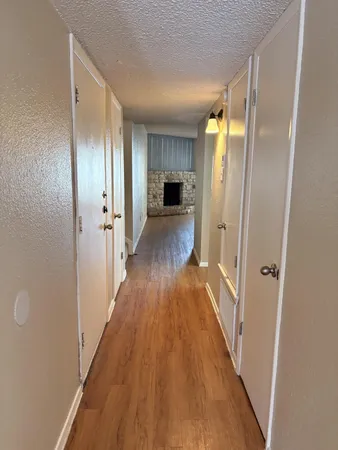 a view of a hallway with wooden floor and a bathroom