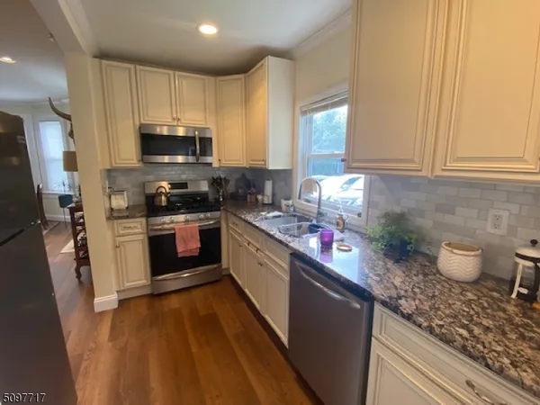 a kitchen with stainless steel appliances a sink a stove a refrigerator cabinets and a window