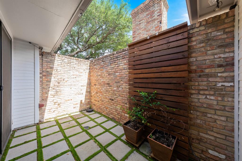 14140 Regency Place Dallas, TX 75254 - Photo 36 of 38 Private outdoor patio featuring concrete pavers with moss ground cover, a brick privacy wall, and a slatted wood screen