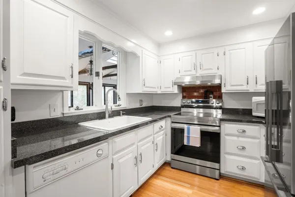 a kitchen with granite countertop a sink stainless steel appliances and cabinets