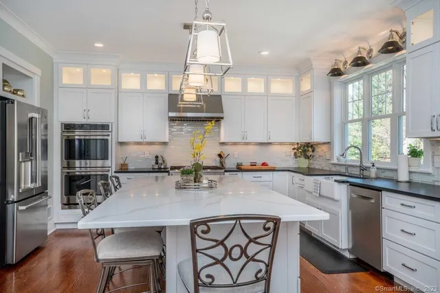 a kitchen with stainless steel appliances a sink a stove a refrigerator cabinets and wooden floor