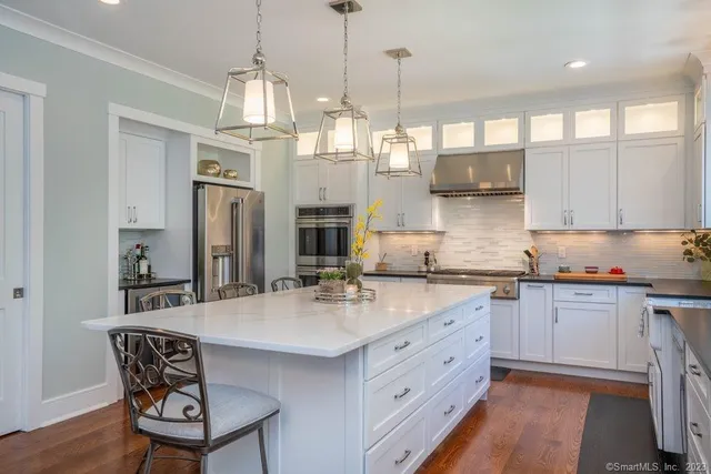 a kitchen with stainless steel appliances granite countertop a sink a stove a refrigerator and island with wooden floor