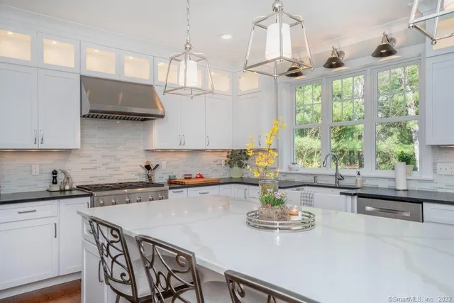 a kitchen with stainless steel appliances a sink a stove a dining table and chairs with wooden floor