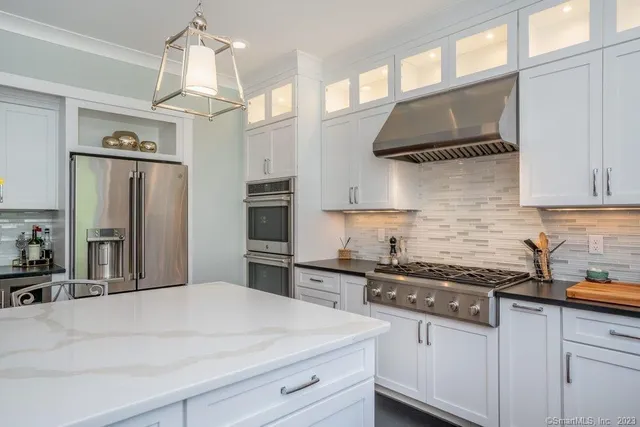 a kitchen with stainless steel appliances a sink a stove a refrigerator and cabinets