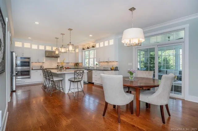 a dining room with wooden floor a chandelier a wooden table and chairs