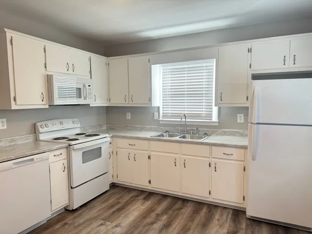 a kitchen with granite countertop white cabinets and white appliances