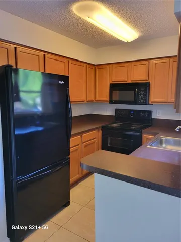 a kitchen with stainless steel appliances kitchen island granite countertop a refrigerator and a microwave