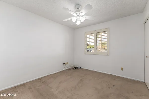 an empty room with a window and a fan