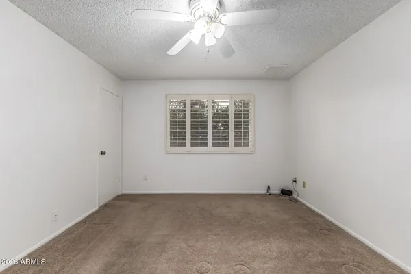 an empty room with a chandelier fan and windows