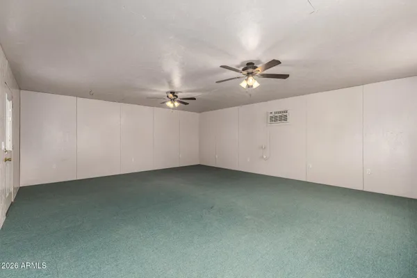 an empty room with chandelier fan and window
