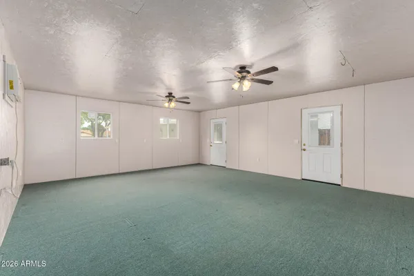 an empty room with windows and fan chandelier