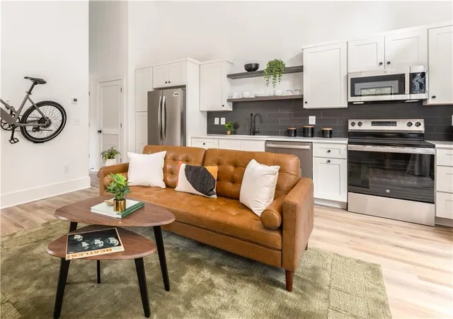 a living room with stainless steel appliances a stove a kitchen island a stove a dining table and chairs