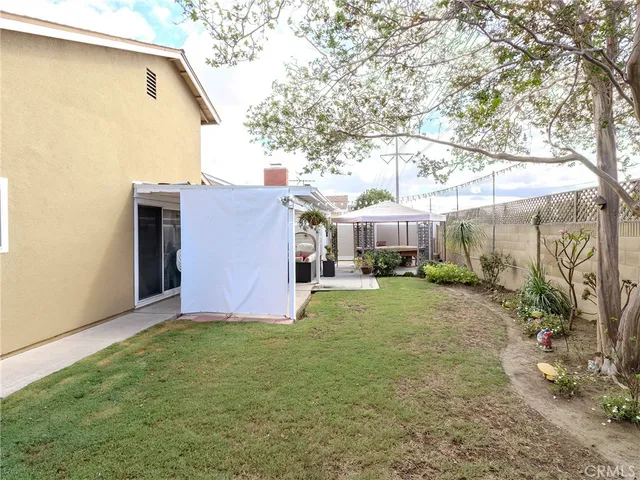 a backyard of a house with table and chairs under an umbrella