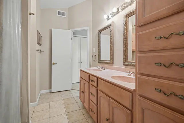a spacious bathroom with a double vanity sink a mirror and a bathtub