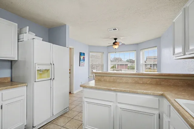 a kitchen with kitchen island white cabinets and refrigerator