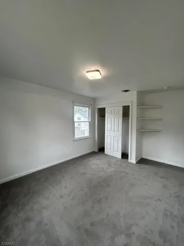 an empty room with a window and closet area