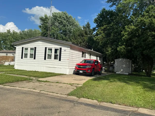 a front view of a house with a garden and trees