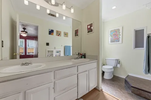 a spacious bathroom with a double vanity sink a mirror and a toilet