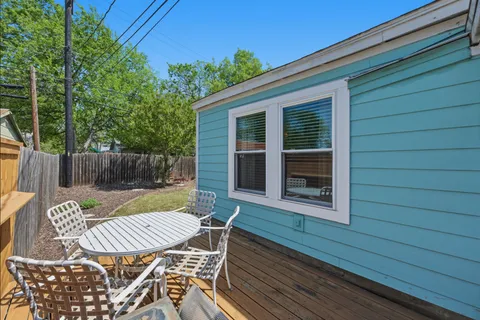a view of a patio with table and chairs with wooden floor and fence