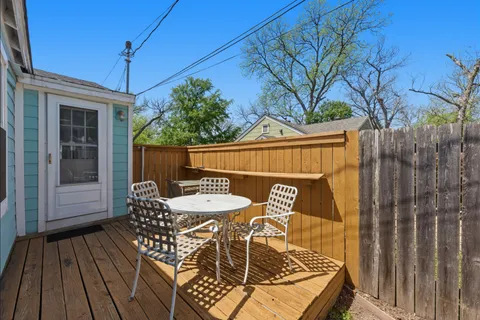 a view of a patio with table and chairs with wooden floor and fence