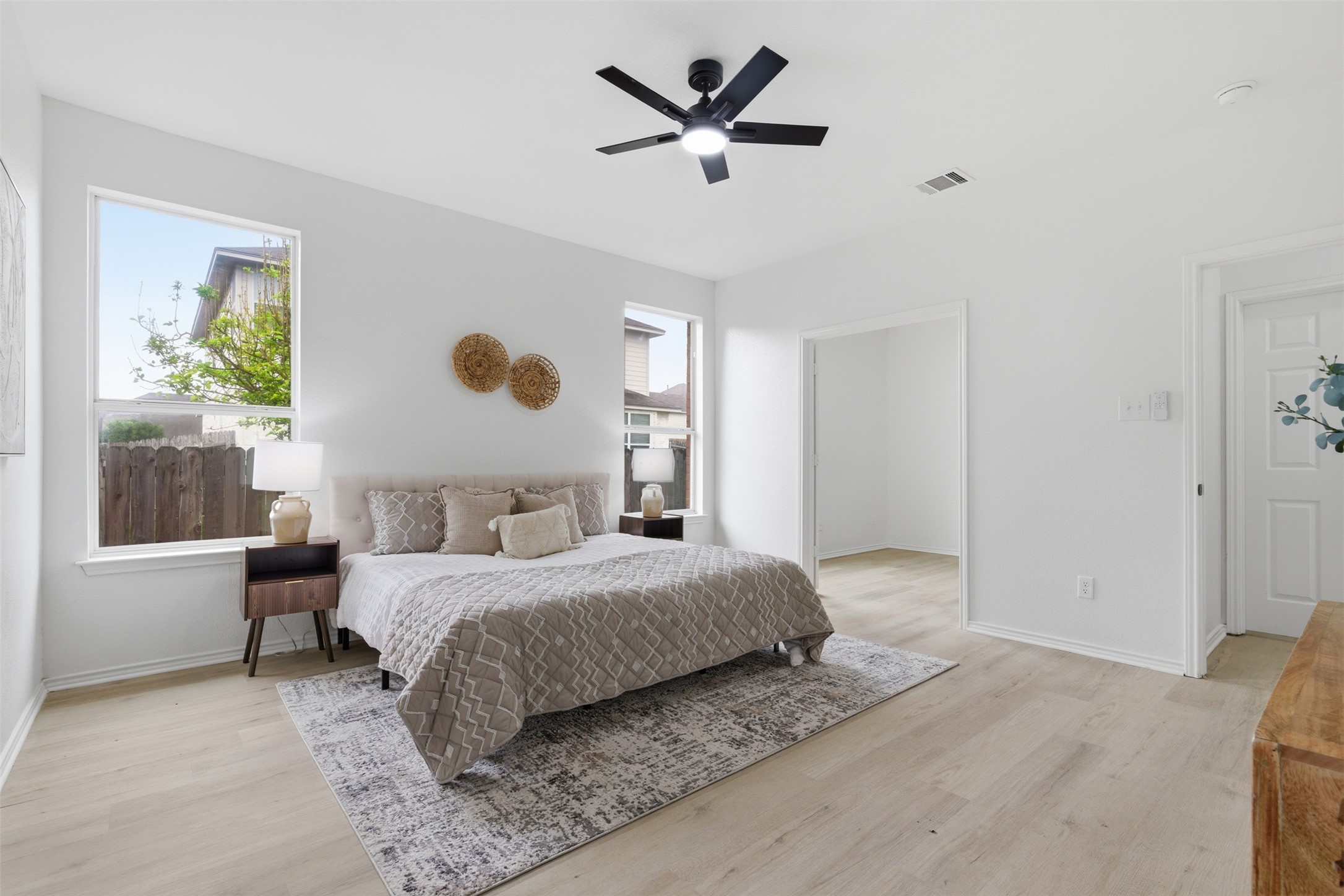 461 Hot Spring Valley Buda, TX 78610 - Photo 10 of 25 This bright bedroom features light-toned flooring, white walls, and a ceiling fan with integrated lighting