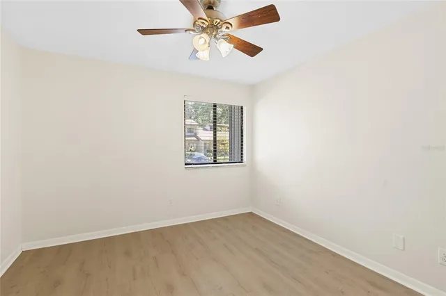 an empty room with a window and ceiling fan
