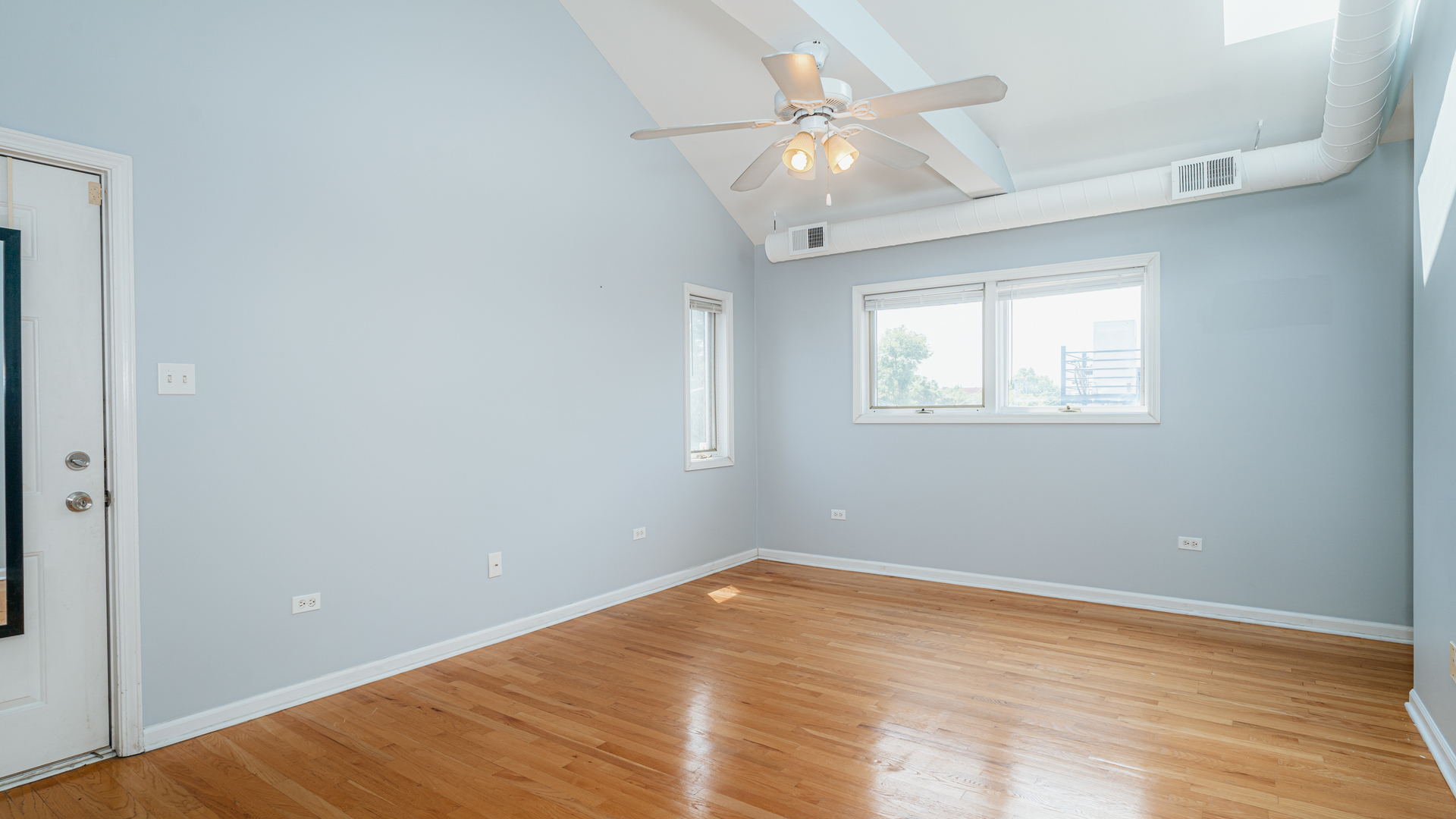 2319 West Harrison Street, Unit 4 Chicago, IL 60612 - Photo 15 of 25 an empty room with wooden floor fan and windows