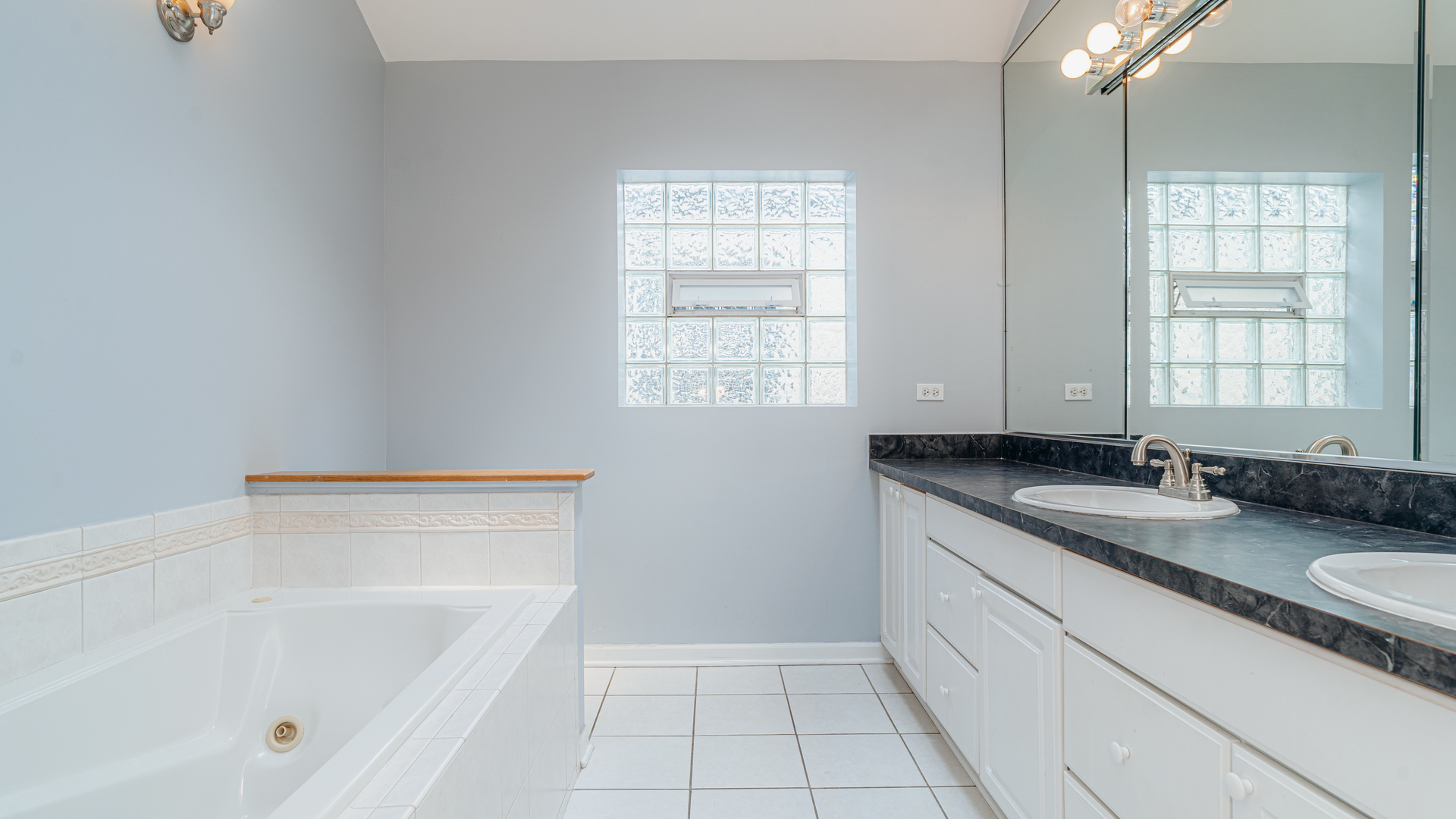 2319 West Harrison Street, Unit 4 Chicago, IL 60612 - Photo 19 of 25 a bathroom with a granite countertop sink a mirror and a bathtub