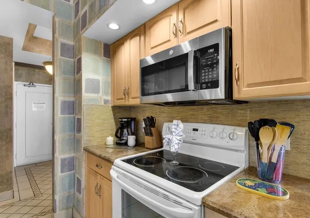 a kitchen with stainless steel appliances granite countertop a sink and a stove next to a cabinet