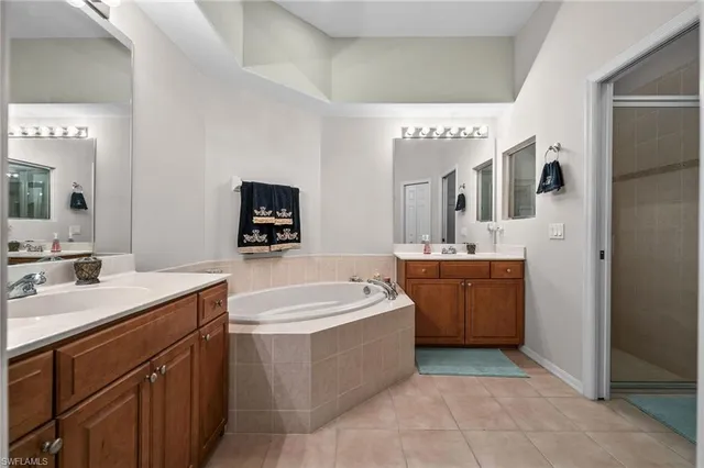 a spacious bathroom with a double vanity sink mirror and bathtub