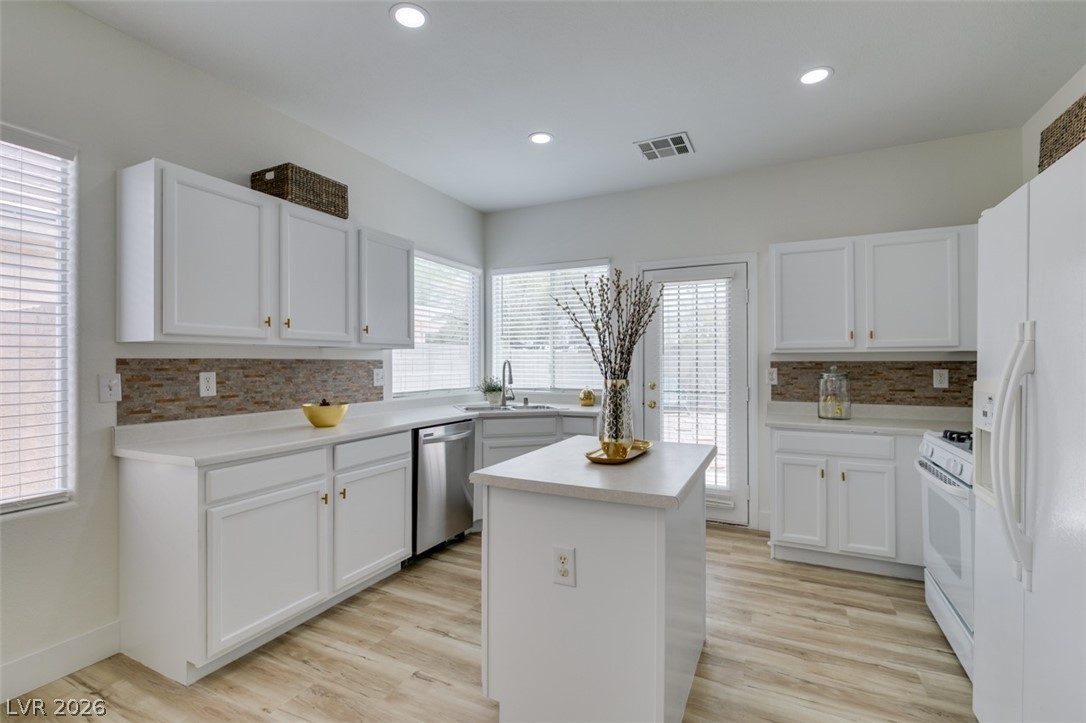 10959 Pumpkin Ridge Avenue Las Vegas, NV 89135 - Photo 14 of 51 A well-lit culinary space features bright white cabinetry, a central island, and stainless steel new microwave and dishwasher