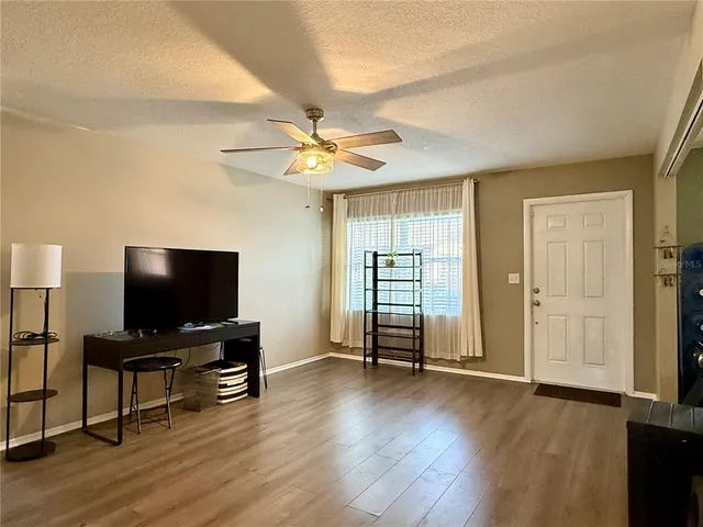 a view of a livingroom with a flat screen tv wooden floor and a ceiling fan