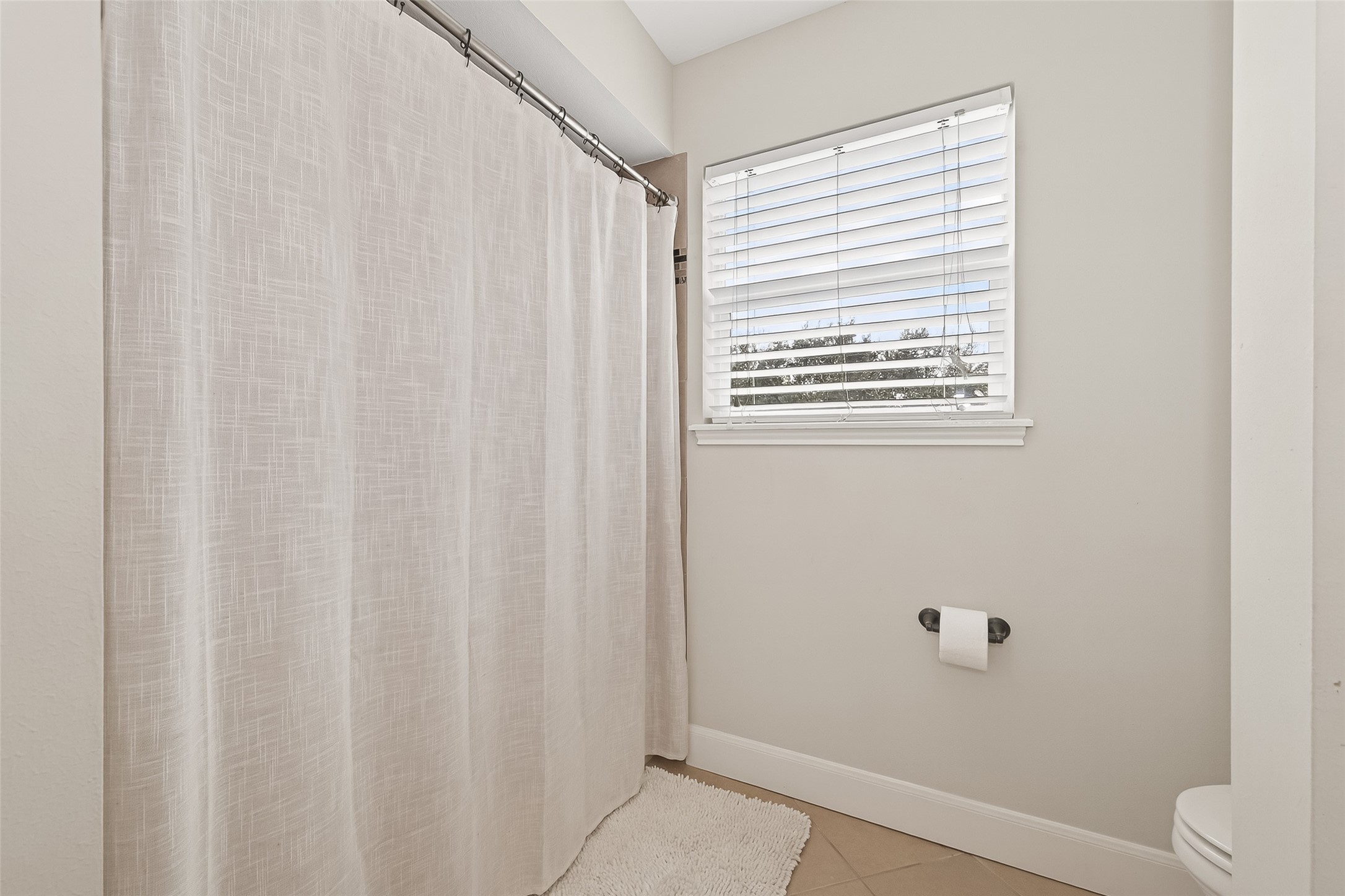 15843 Foxgate Road Houston, TX 77079 - Photo 37 of 49 a bathroom with a window and a shower curtain