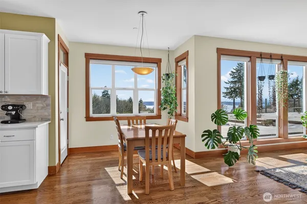 a dining room with wooden floor a chandelier a glass table and chairs