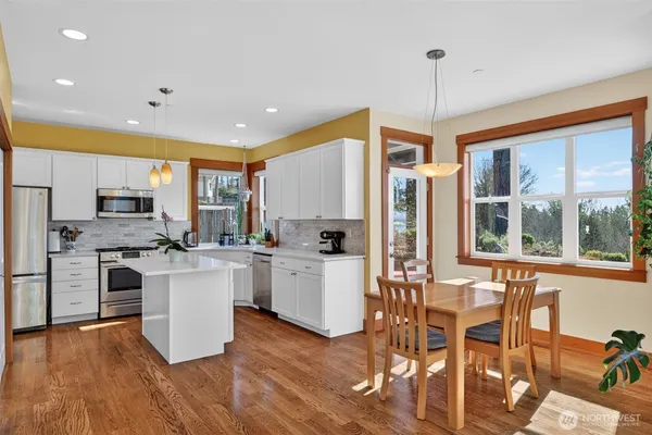 a kitchen with stainless steel appliances granite countertop a stove top oven a refrigerator a sink and a dining table with wooden floor