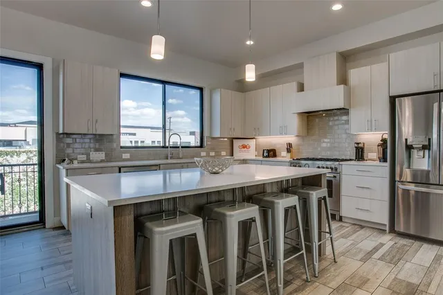 a kitchen with stainless steel appliances granite countertop a table chairs sink refrigerator and cabinets