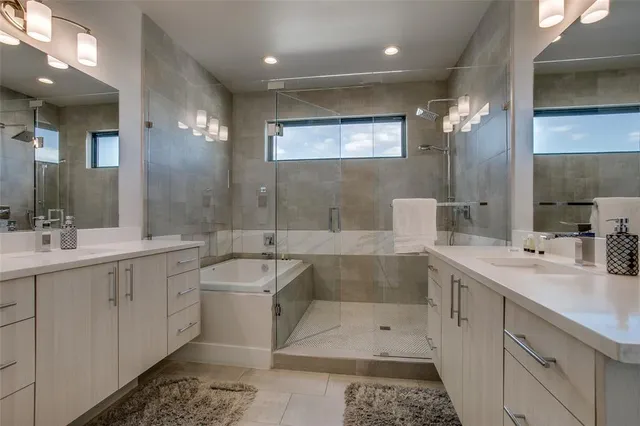 a bathroom with a double vanity sink a large mirror and a bathtub