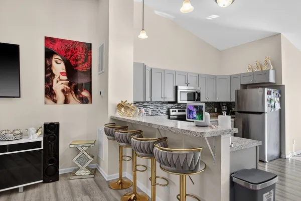 a kitchen with stainless steel appliances a stove a refrigerator and a dining table with chairs