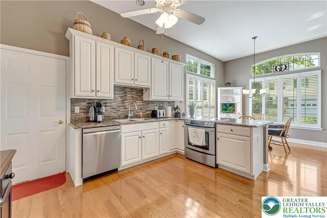 a white kitchen with stainless steel appliances granite countertop a refrigerator a sink dishwasher a stove and white countertops with cabinets