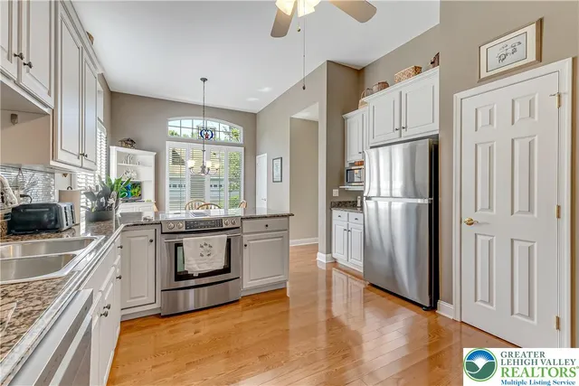 a kitchen with stainless steel appliances granite countertop a stove a sink and a white refrigerator with wooden floor