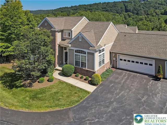 an aerial view of residential house with outdoor space and trees all around