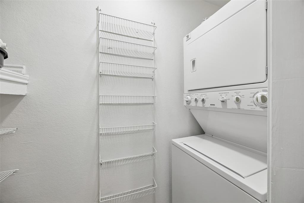12660 Hillcrest Road, Unit 7205 Dallas, TX 75230 - Photo 20 of 25 Dedicated laundry area featuring a stacked washer and dryer unit, vertical wire shelving, and crisp white walls