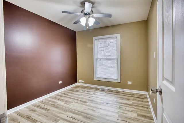 an empty room with a window and ceiling fan